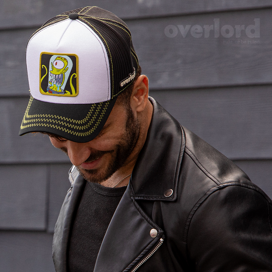 Man wearing white and black OVERLORD X The Simpsons present Kang the alien trucker baseball cap hat with lime green zig zag stitching. PVC Overlord logo.