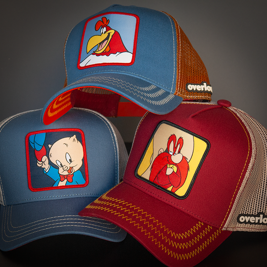 Blue OVERLORD X Looney Tunes Porky Pig holding a hat trucker baseball cap hat with cream stitching. PVC Overlord logo.