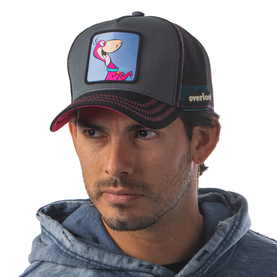 Man wearing steel blue and black OVERLORD X Flintstones Dino trucker baseball cap with hot pink zig zag stitching. PVC Overlord logo.