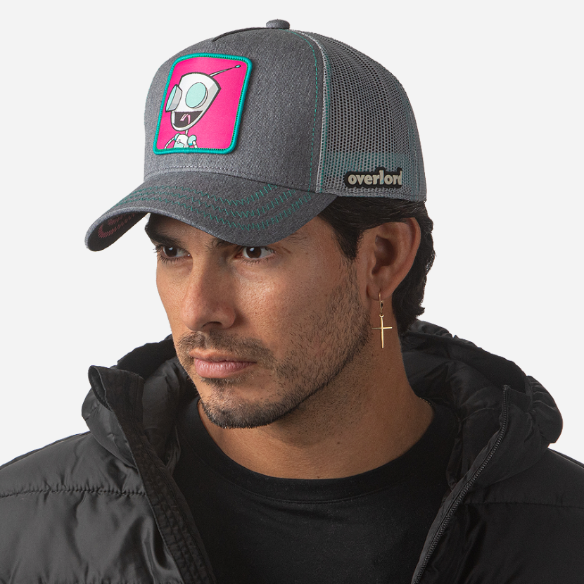 Man wearing heather gray OVERLORD X Invader Zim GIR robot trucker baseball cap hat with turquoise zig zag stitching. PVC Overlord logo.