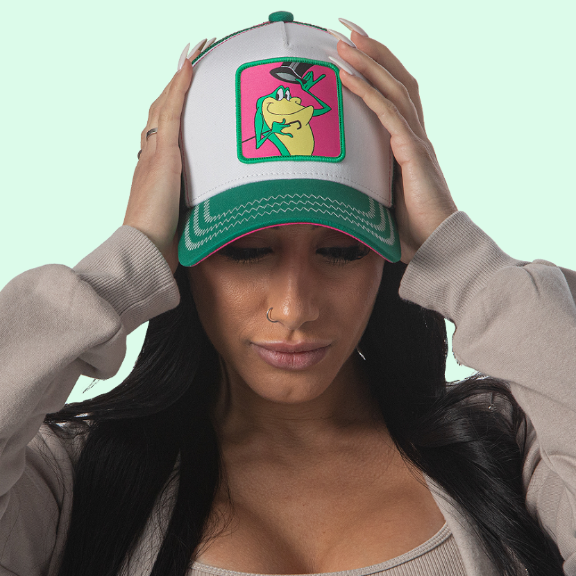 Woman wearing white and green OVERLORD X Looney Tunes Michigan J. Frog trucker baseball cap hat with white zig zag stitching. PVC Overlord logo.