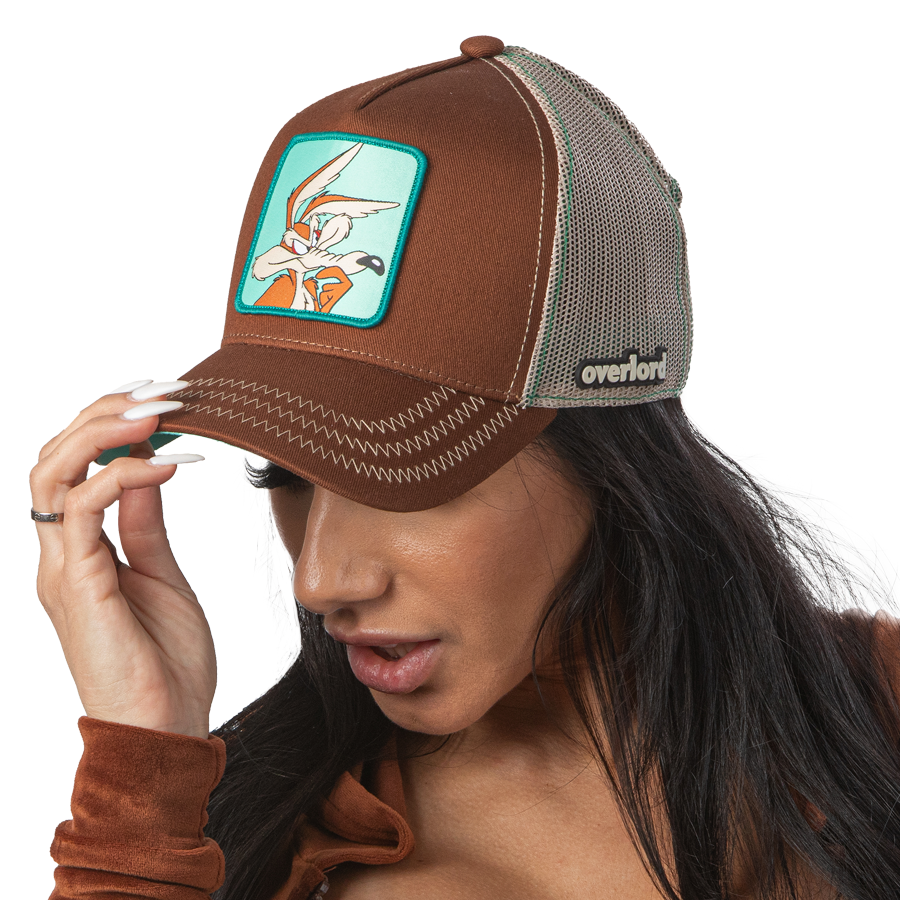 Woman wearing brown OVERLORD X Looney Tunes thinking Wile E. Coyote trucker baseball cap hat with khaki zig zag stitching. PVC Overlord logo.