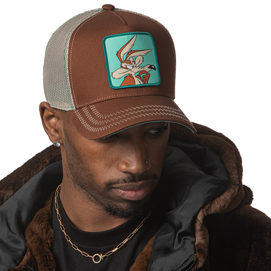Man wearing brown OVERLORD X Looney Tunes thinking Wile E. Coyote trucker baseball cap hat with khaki zig zag stitching. PVC Overlord logo.