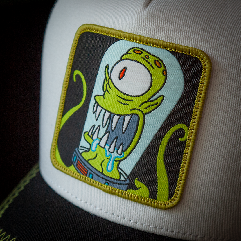 White and black OVERLORD X The Simpsons present Kang the alien trucker baseball cap hat woven Overlord patch closeup.