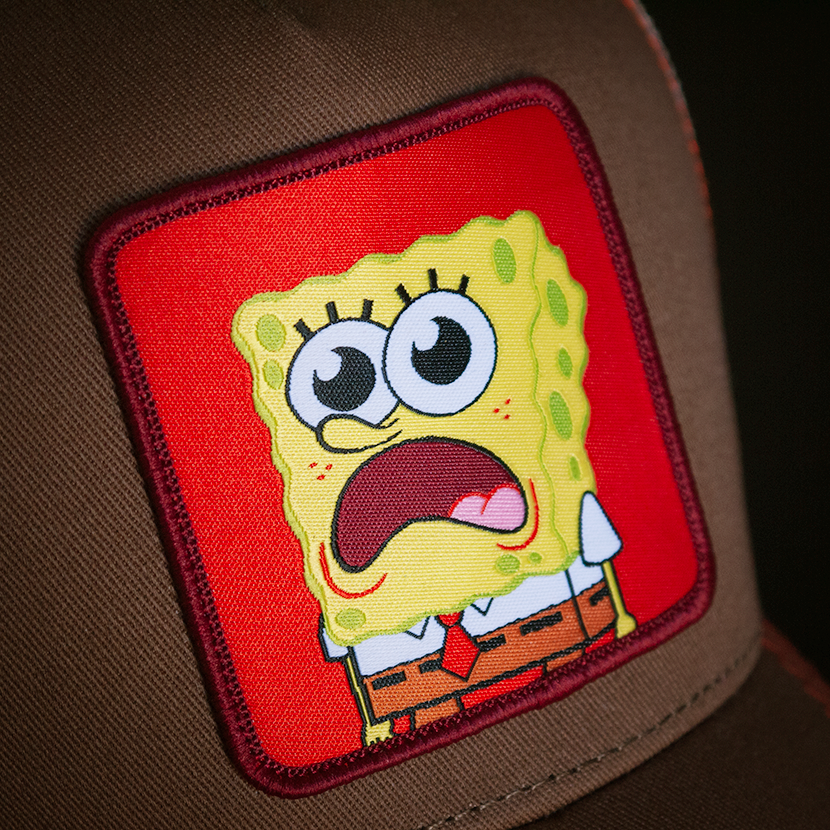 Brown OVERLORD X SpongeBob surprised face trucker baseball cap hat woven Overlord patch closeup.