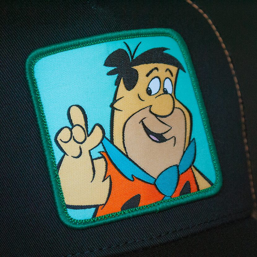 Black OVERLORD X Flintstones Fred Flintstone trucker baseball cap woven Overlord patch closeup.