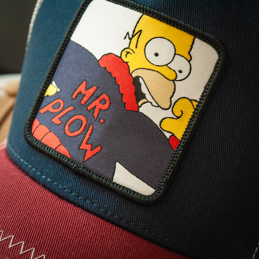 Navy and red OVERLORD X The Simpsons Homer Mr. Plow trucker baseball cap hat woven Overlord patch closeup.