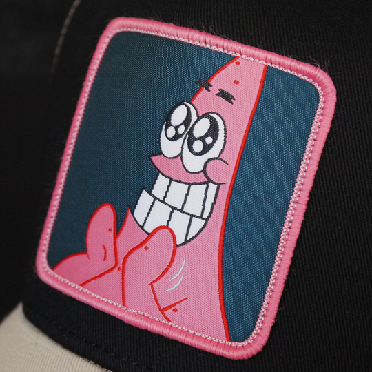 Black and tan OVERLORD X SpongeBob Big Smile Patrick trucker baseball cap hat woven Overlord patch closeup.
