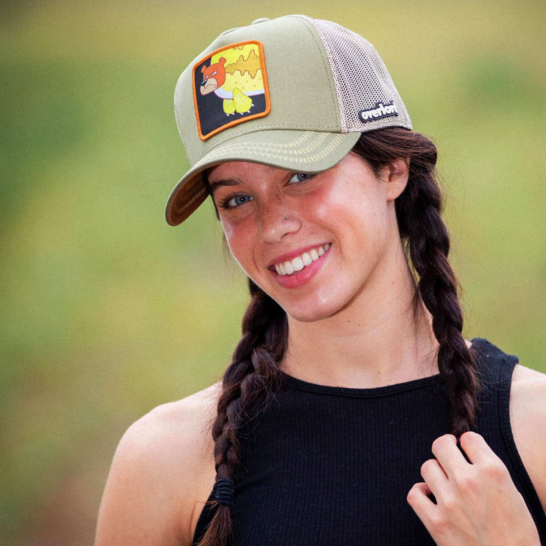 Woman wearing olive green OVERLORD X SpongeBob Seabear trucker baseball cap hat with light olive zig zag stitching. PVC Overlord logo.