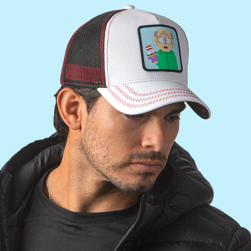 Man wearing white OVERLORD X South Park Mr. Garrison trucker baseball cap hat with red zig zag stitching. PVC Overlord logo.