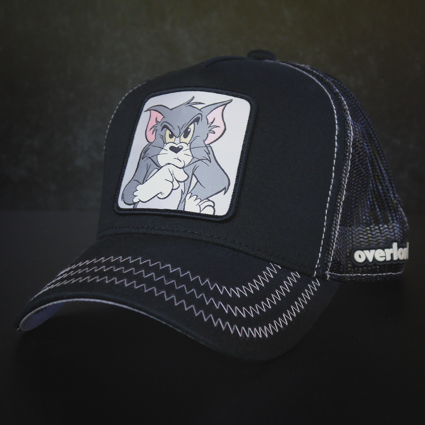 Black OVERLORD X Tom and Jerry Tom cat trucker baseball cap hat with gray zig zag stitching. PVC Overlord logo.